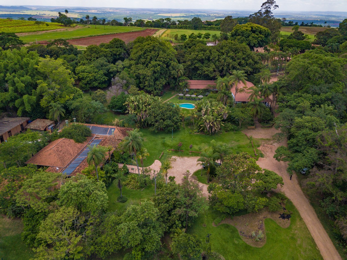 Vista aérea da piscina entre o verde da fazenda