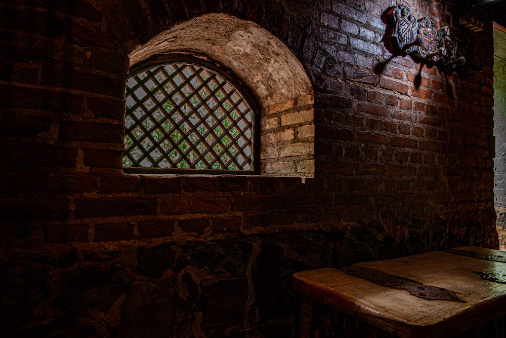 Cave de tijolos com janela em arco e mesa de madeira