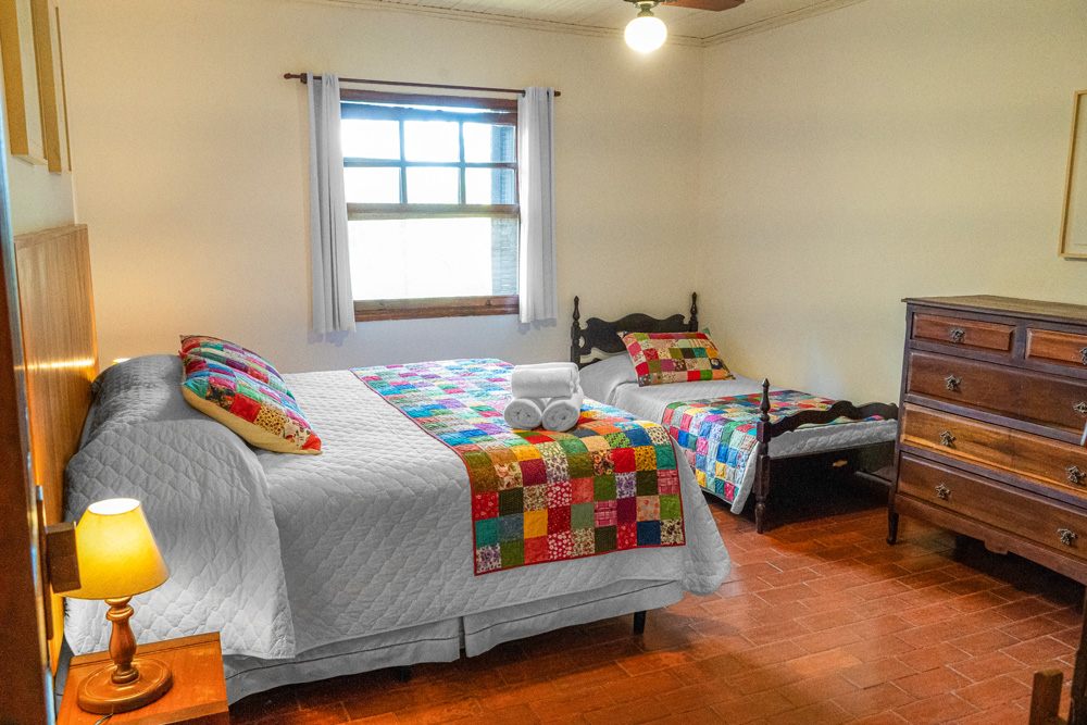 Quarto com cama de casal e de solteiro do Chalé 5
