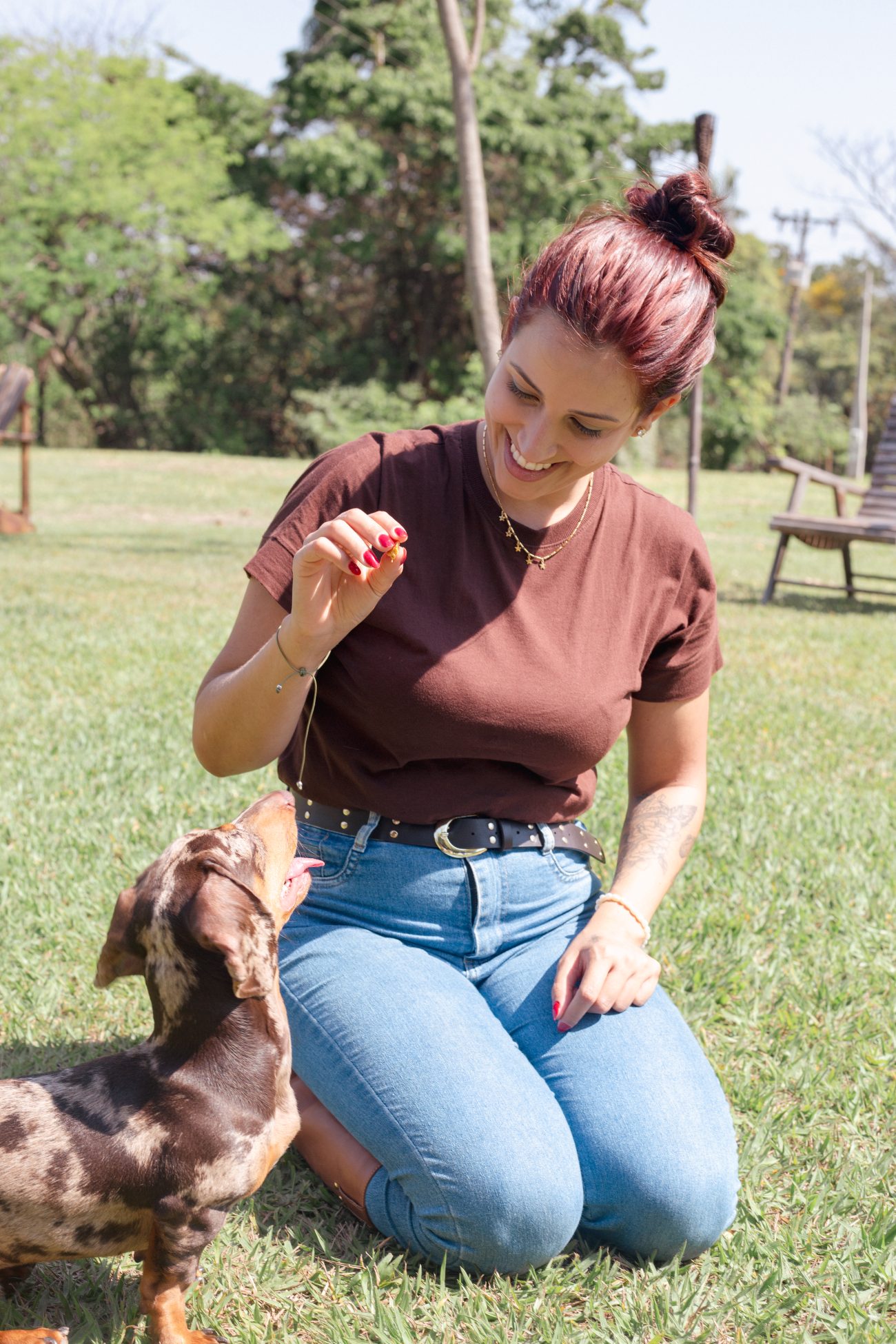 Hóspede oferecendo um petisco a um cachorro no gramado da fazenda