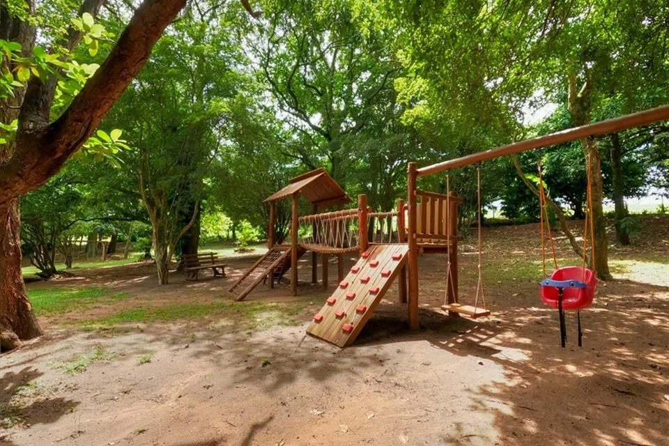 Playground com escorregador, escalada e balanço à sombra