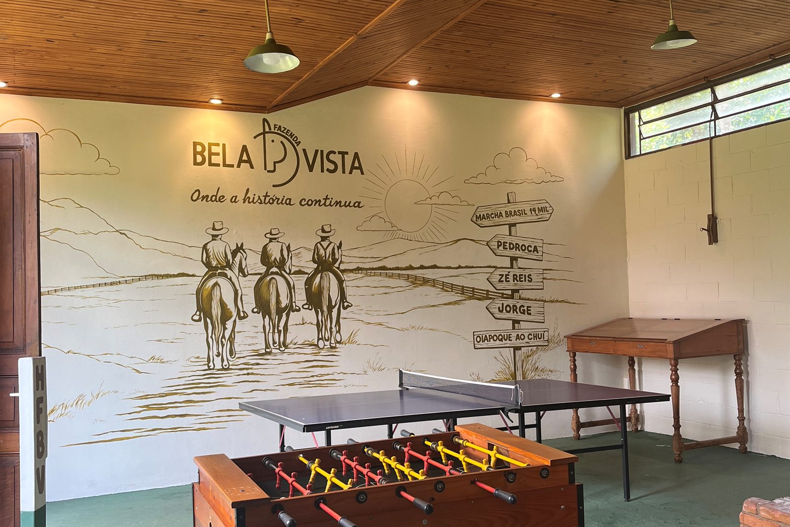 Salão de jogos com mesa de pingue-pongue, pebolim e mural da Bela Vista